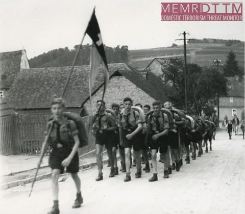 A group of people marching with a flagDescription automatically generated with low confidence